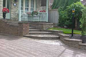 Landscaping Design that uses a natural stone wall edging between garden and the driveway